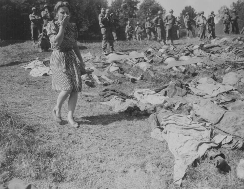 O fată germană este depășită în timp ce trece pe lângă corpurile exhumate