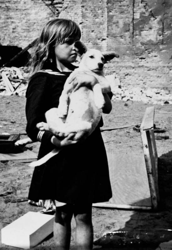 A girl holding her dog in a devastated neighborhood in Warsaw, Poland, 5 Sep 1939