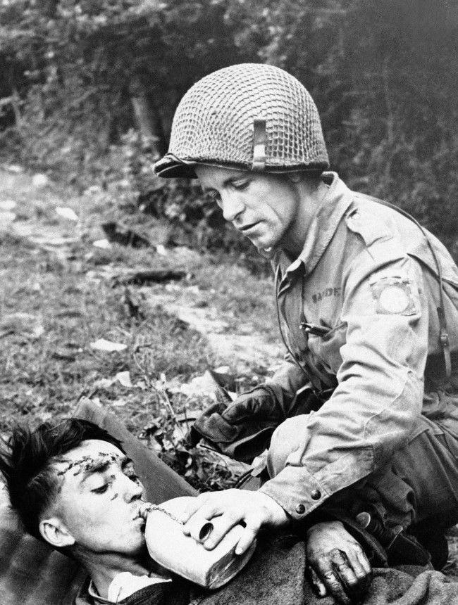 American soldier gives a drink of water to a wounded German prisoner